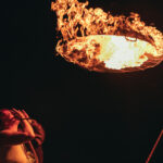 Person looking up at ball of fire at night.